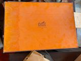 une boîte orange posée sur une table en bois, à côté d'un sac marron