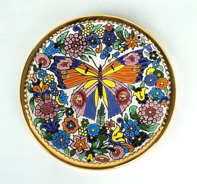 une assiette colorée ornée d'un papillon, posée sur un fond blanc