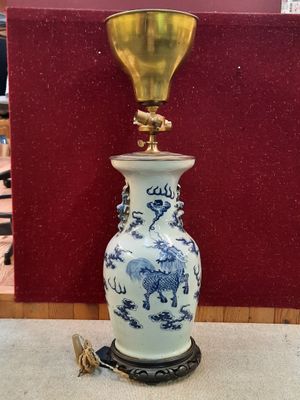 un vase bleu et blanc sur lequel est posée une lampe dorée