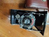 an old camera sitting on a wooden floor next to a wallet