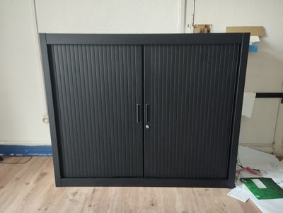 Une armoire métalliques basses 2 portes à rideaux.