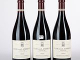 trois bouteilles de vin rouge posées sur une table blanche