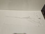 a piece of white paper on the floor next to a pair of scissors