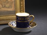 une tasse et une soucoupe posées sur une table, à côté d'un tableau