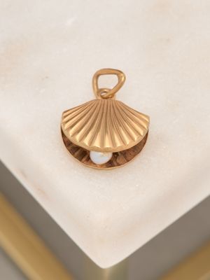 a gold shell with a pearl in it on a marble surface