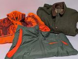 three jackets and a hat sitting on a table