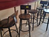 four wooden stools sitting in front of a bar