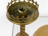 a gold plate with a candle on it on a glass table