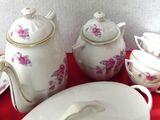 a red table cloth with a bunch of white dishes and cups