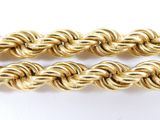 a close up of two gold rope chains on a white surface