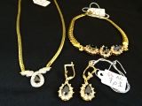 trois bijoux posés sur un tissu noir, accompagnés d'une étiquette de prix