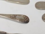 five spoons and two forks on a white table