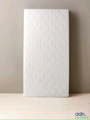a white mattress sitting on top of a wooden table next to a wall