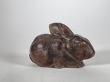 a brown rabbit figurine sitting on top of a white surface