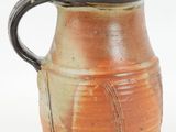 a brown and black vase with a handle on a white background
