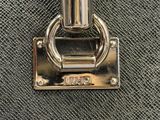 the handle of a black purse with a metal ring on it