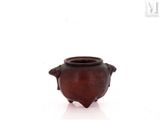 a small brown vase with a handle on a white surface