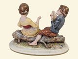 a figurine of a boy and a girl sitting on a log