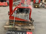 une machine rouge posée sur une palette dans un entrepôt