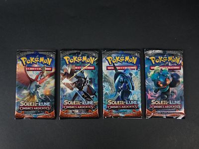 trois paquets de cartes à collectionner Pokémon posés sur une surface noire