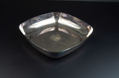 une assiette en argent posée sur une table noire, sur fond noir
