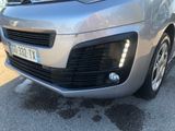 the front end of a silver van parked in a parking lot