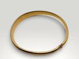 a gold bang bracelet with a small bead on it