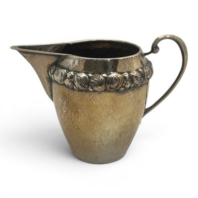 a silver pitcher that is sitting on a white surface