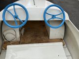 a small boat with two blue steerings on the deck