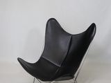 fauteuil papillon en cuir noir avec des pieds en acier chromé