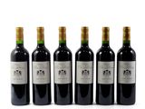 six bottles of wine are lined up in a row on a white surface