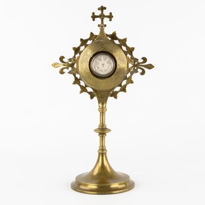 an antique brass clock on a stand on a white background