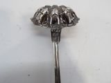 a silver spoon with a flower on it on a white surface