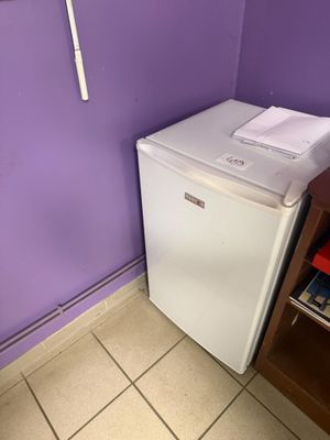 des murs violets dans une petite pièce où se trouvent un réfrigérateur blanc et une étagère