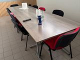 des tables et des chaises dans une pièce où est accrochée une télévision à écran plat au mur