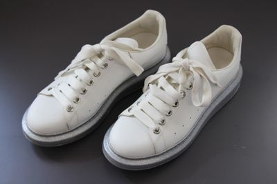 pair of white sneakers on a black surface with a black background