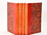 trois livres rouges sont empilés sur une surface blanche