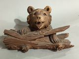 a wooden sculpture of a bear holding a piece of wood