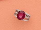 un gros plan d'une bague ornée d'une pierre rouge entourée de perles