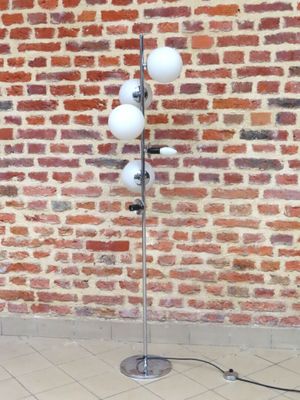une lampe posée sur un pied devant un mur de briques