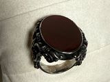 a ring with a black stone on it on a pillow