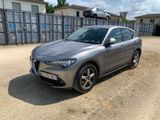 La voiture grise est garée devant un espace clôturé.