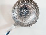 a silver measuring spoon with a blue handle on a white surface