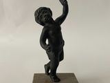 statue représentant un petit garçon assis sur un bloc de bois, tenant une raquette de tennis