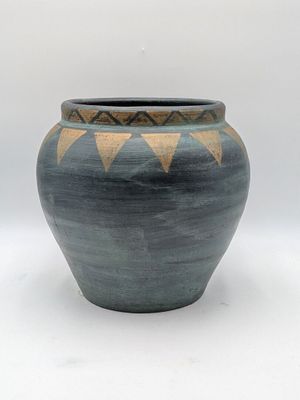 un vase bleu et brun posé sur une surface blanche