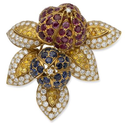a close up of a flower brooch with diamonds and sapphires