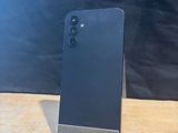 the back of a black cell phone sitting on top of a wooden table