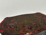 an old black and red box sitting on top of a white surface