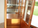 a wooden cabinet with a glass door in the corner of the room