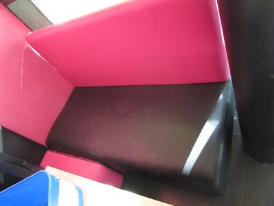 une chaise rose et noire posée à côté d'une poubelle bleue